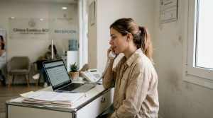 Recepcionista respondiendo una llamada en la recepción de una clínica de estética